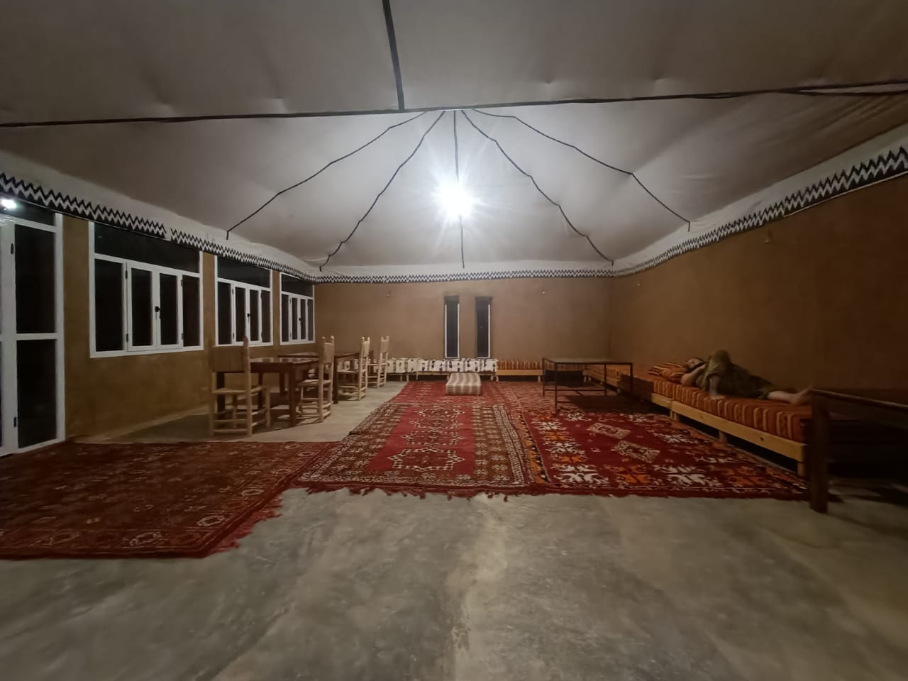 Interior of a desert camp lounge with patterned carpets tables chairs and cushioned seating