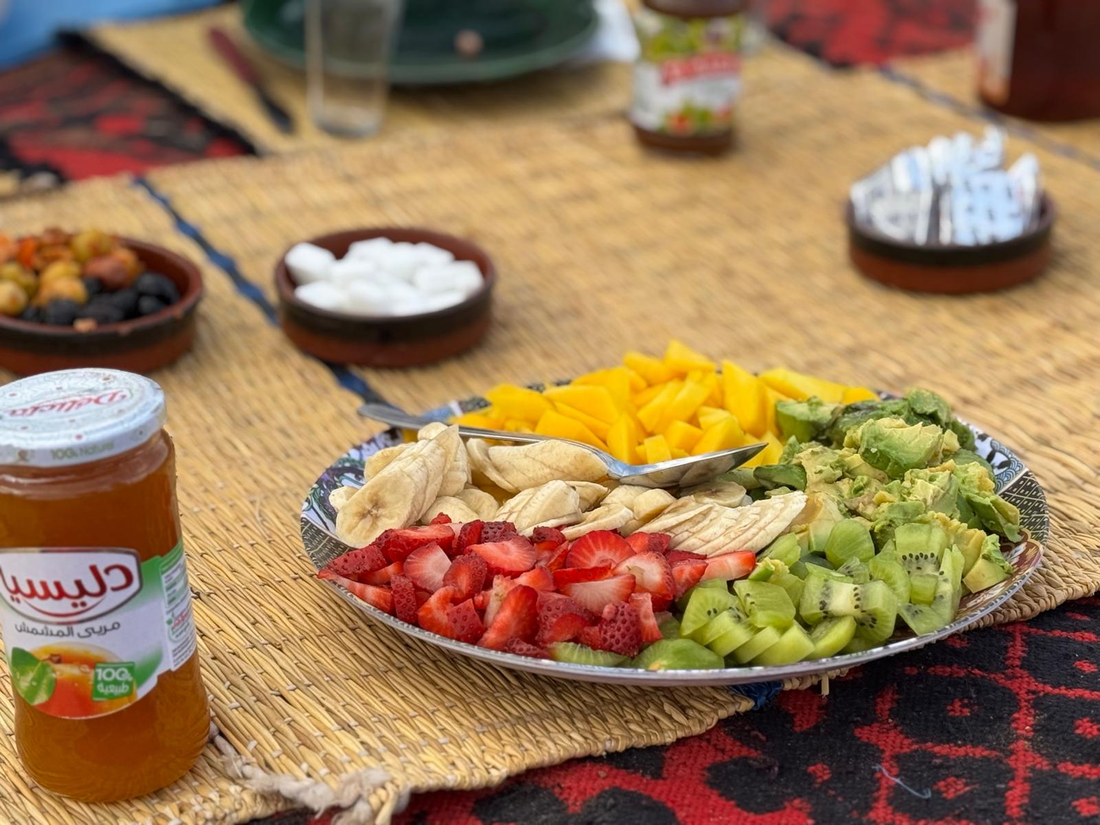 Plate of fresh fruit including strawberries kiwi banana mango and avocado on a woven mat